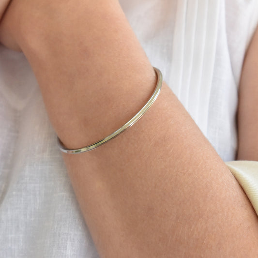 Slender steel bracelet on a person's wrist with a white background