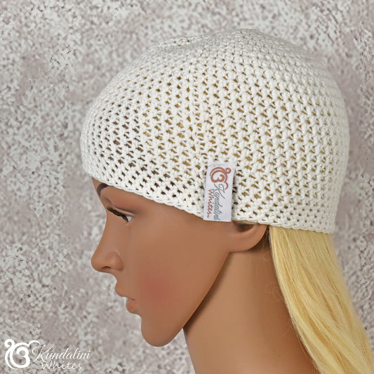 Close-up of a mannequin wearing a white knitted hat with a visible brand tag against a textured gray background.
