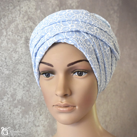 Mannequin head wearing a blue and white patterned turban against a neutral background