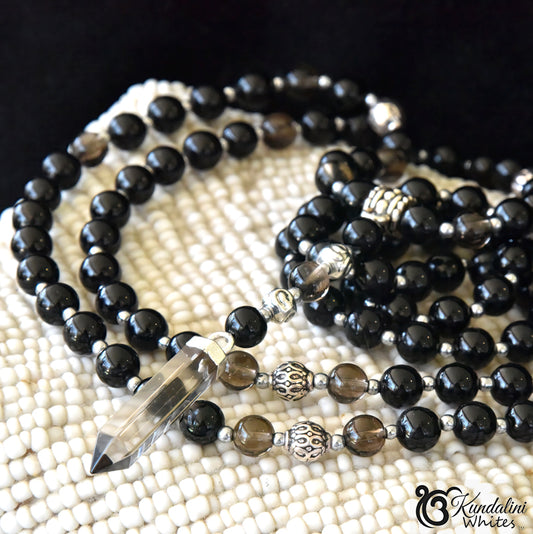 Black beaded necklace with a crystal pendant on a textured surface