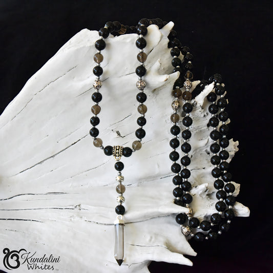 Black beaded necklace with a crystal pendant on a white shell against a black background