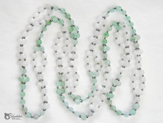 A fluorite and white jade Tantric Mala, with small metallic silver spacer beads throughout, laid out on a plain white background.