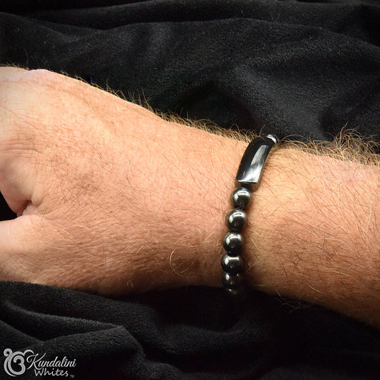 Close-up of a wrist wearing a black beaded bracelet against a black background
