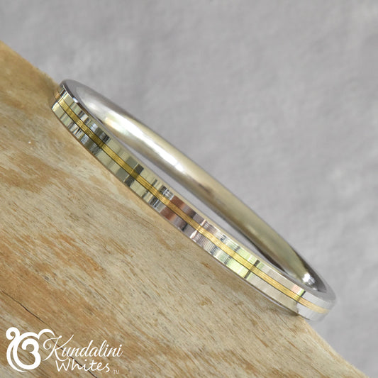 Silver and gold Kara on a wooden surface with a gray background