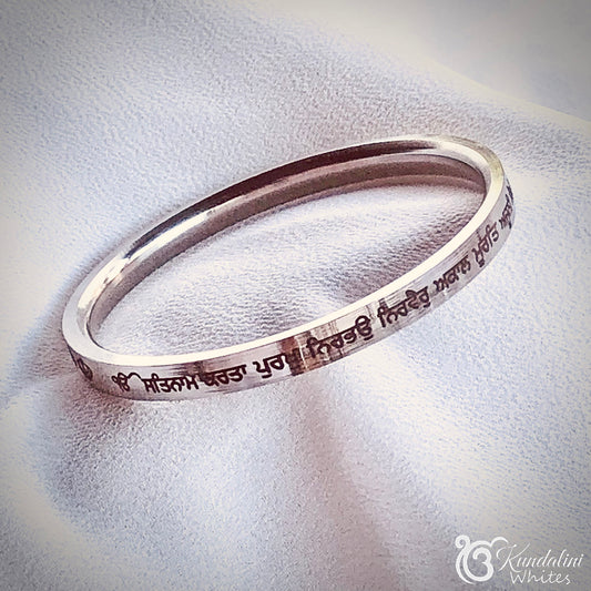 Steel bracelet with engraved text on a white fabric background