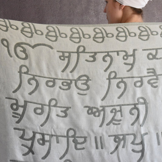 Person holding a blanket with text in a non-Latin script against a gray background