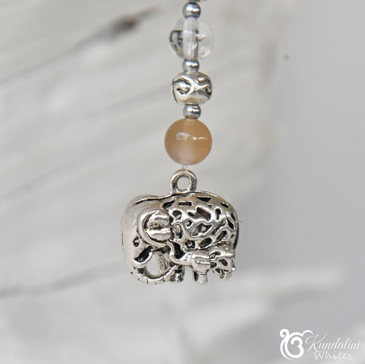 Silver elephant charm with beads on a blurred background