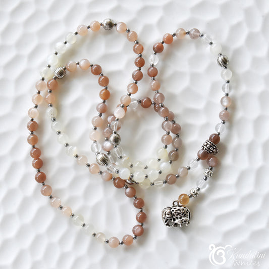 Beaded moonstone necklace with a silver pendant on a white textured surface