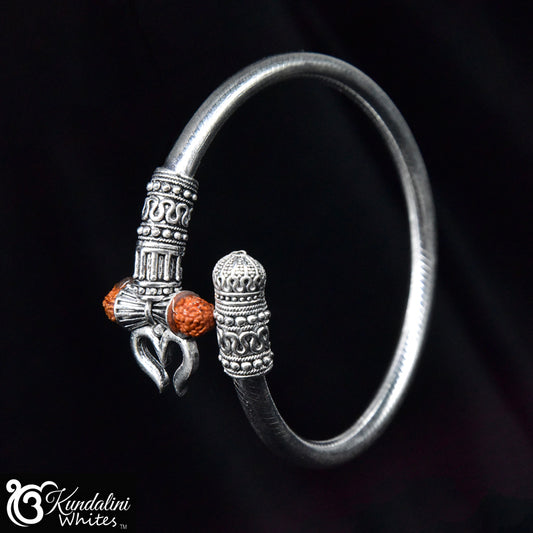 Silver bracelet with intricate designs and orange beads on a black background