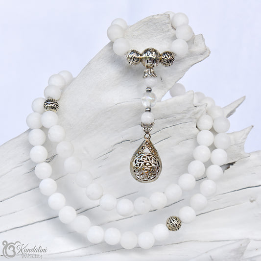 White beaded necklace with silver teardrop pendant on a white background