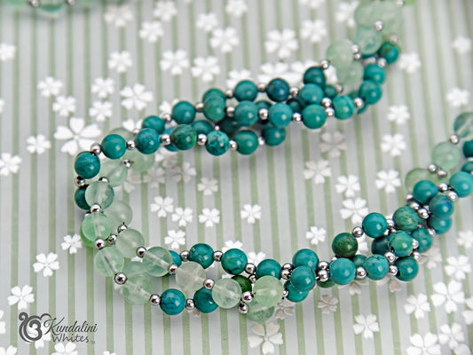 Green beaded tantric mala with silver accents on a floral patterned background