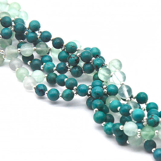 Beaded necklace with green and white beads on a white background