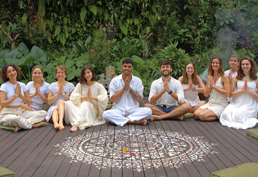 Group of yogis dressed in white, sitting with hands in gyan mudra