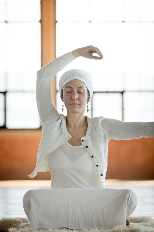 Woman in sitting meditation wearing white clothing