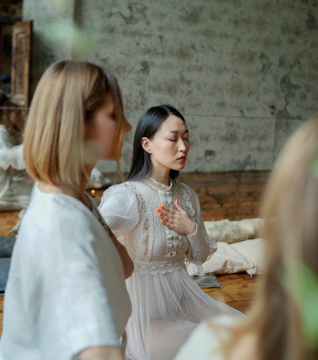 Woman meditating with left hand on her heart, dressed in white