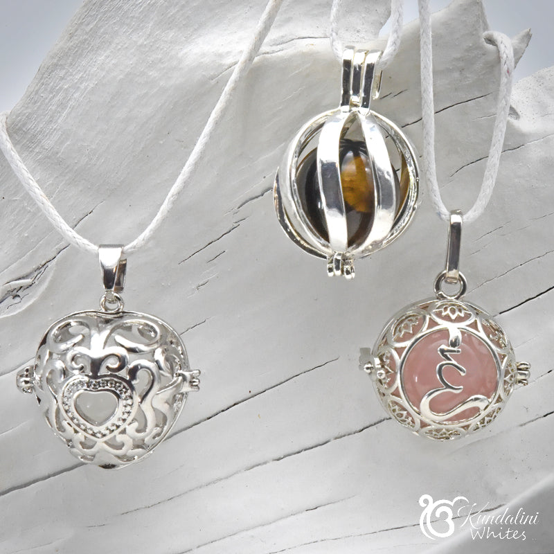 Three silver pendants on white ribbons against a light wooden background