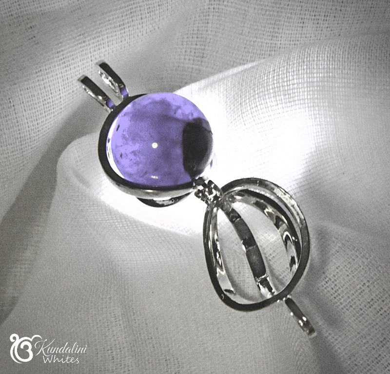 Purple gemstone pendant on a silver chain against a textured white background