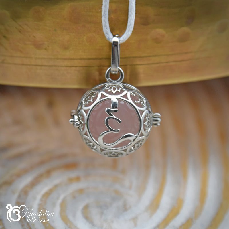 Silver pendant with intricate design on a wooden surface