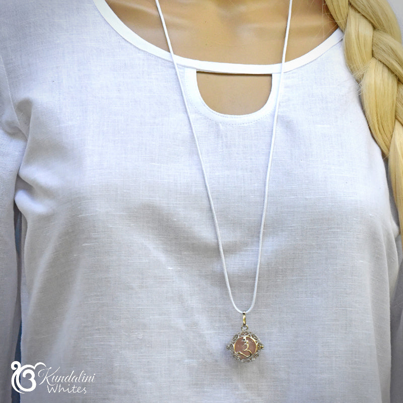Necklace with a pendant on a white shirt, brand 'Kundalini Whites' visible