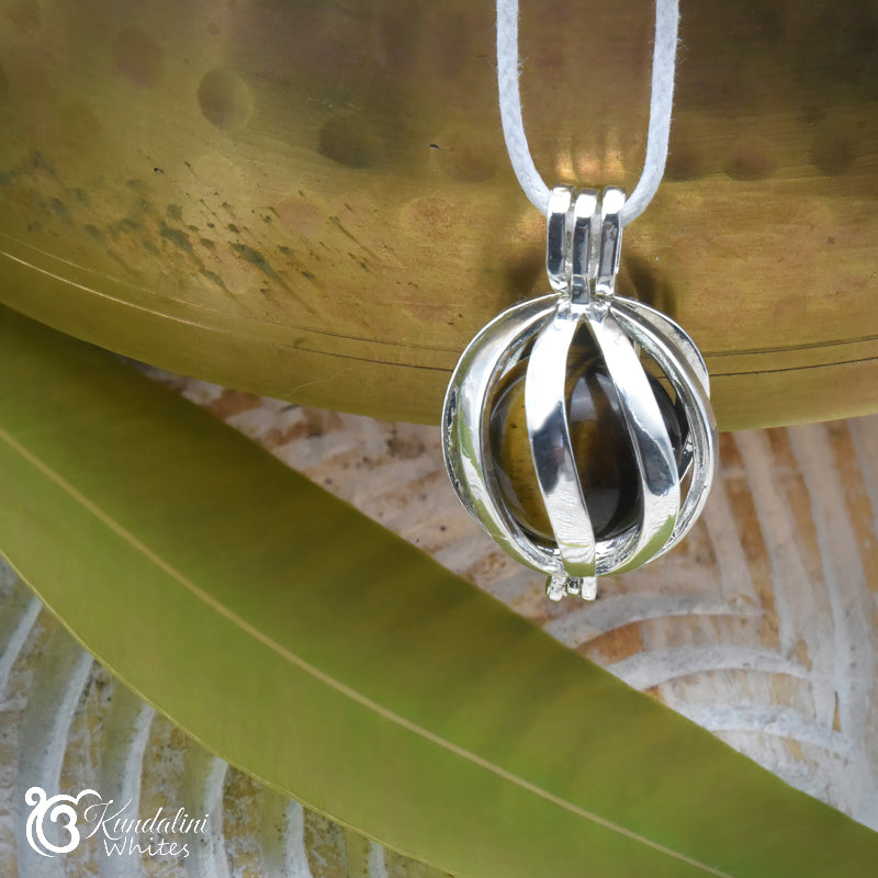 Silver pendant on a white cord against a textured surface