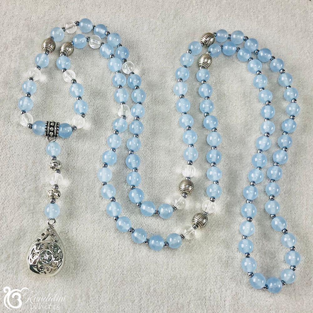 Blue beaded Mala necklace with silver accents on a textured surface