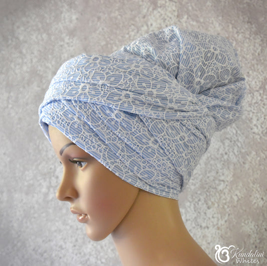 Mannequin head wearing a blue patterned turban against a neutral background