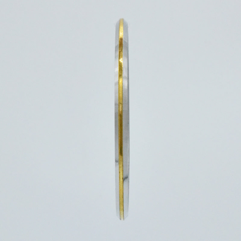 Sideview of steel and brass kara on a light gray background