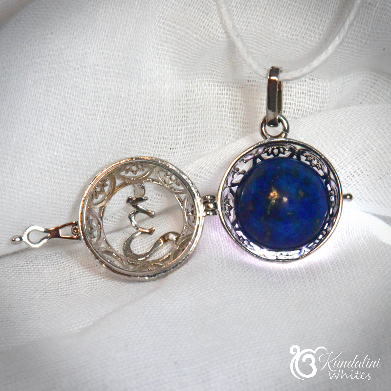 Silver pendant with blue stone on a white fabric background
