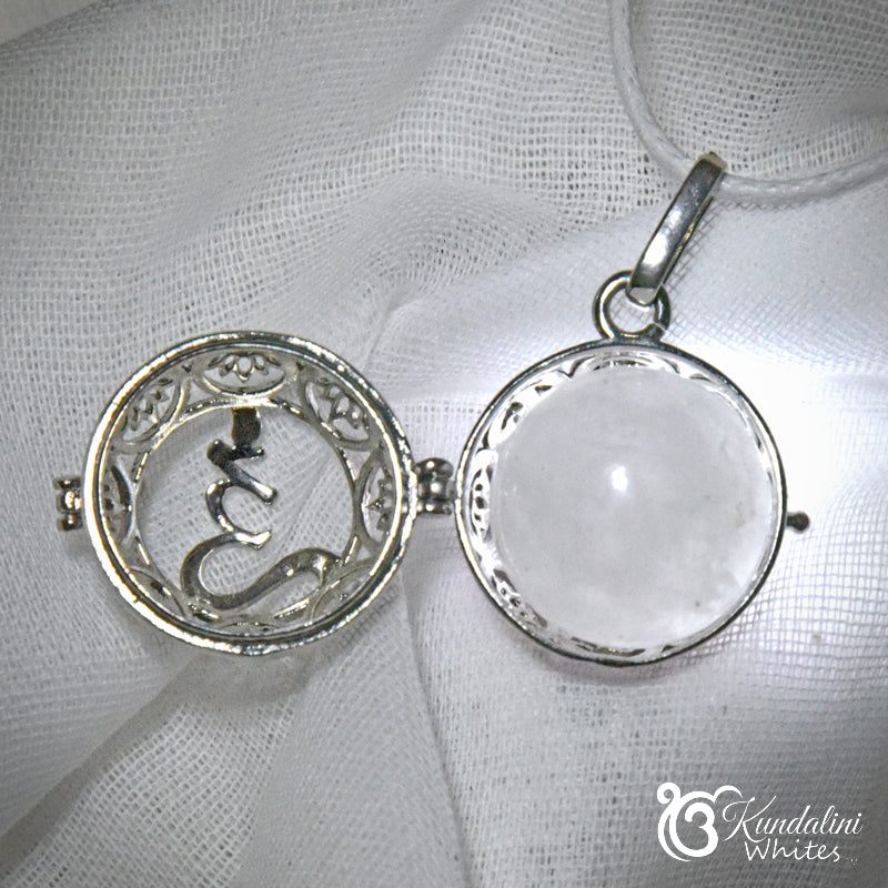 Two silver pendants on a white fabric background with 'Kundalini Whites' branding.