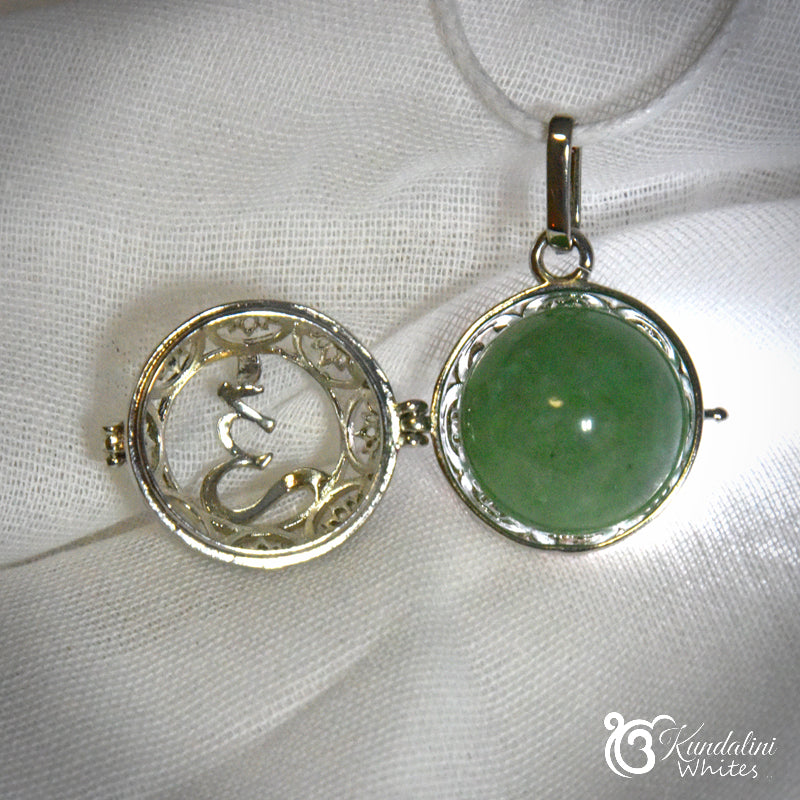 Jewelry set with a green gemstone pendant and silver mermaid design on a white fabric background.