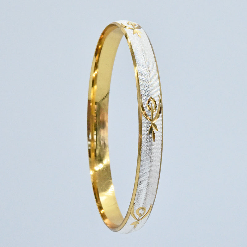 Gold and silver coloured alloy bracelet with intricate designs on a light gray background