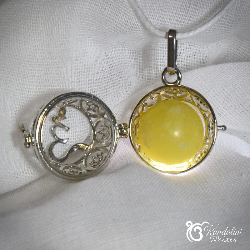Two circular pendants on a white fabric background, one with intricate detailing and the other with a yellow center.