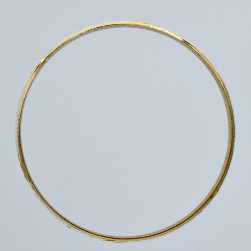 Gold and silver coloured kara on a light gray background