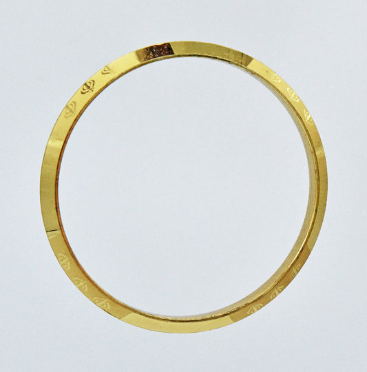 Gold coloured alloy bracelet on a light gray background