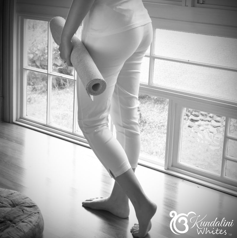 Person holding a yoga mat in a room with large windows