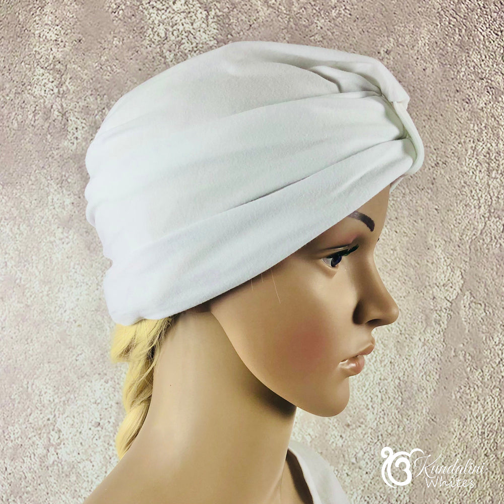 White turban on a mannequin head against a textured beige background