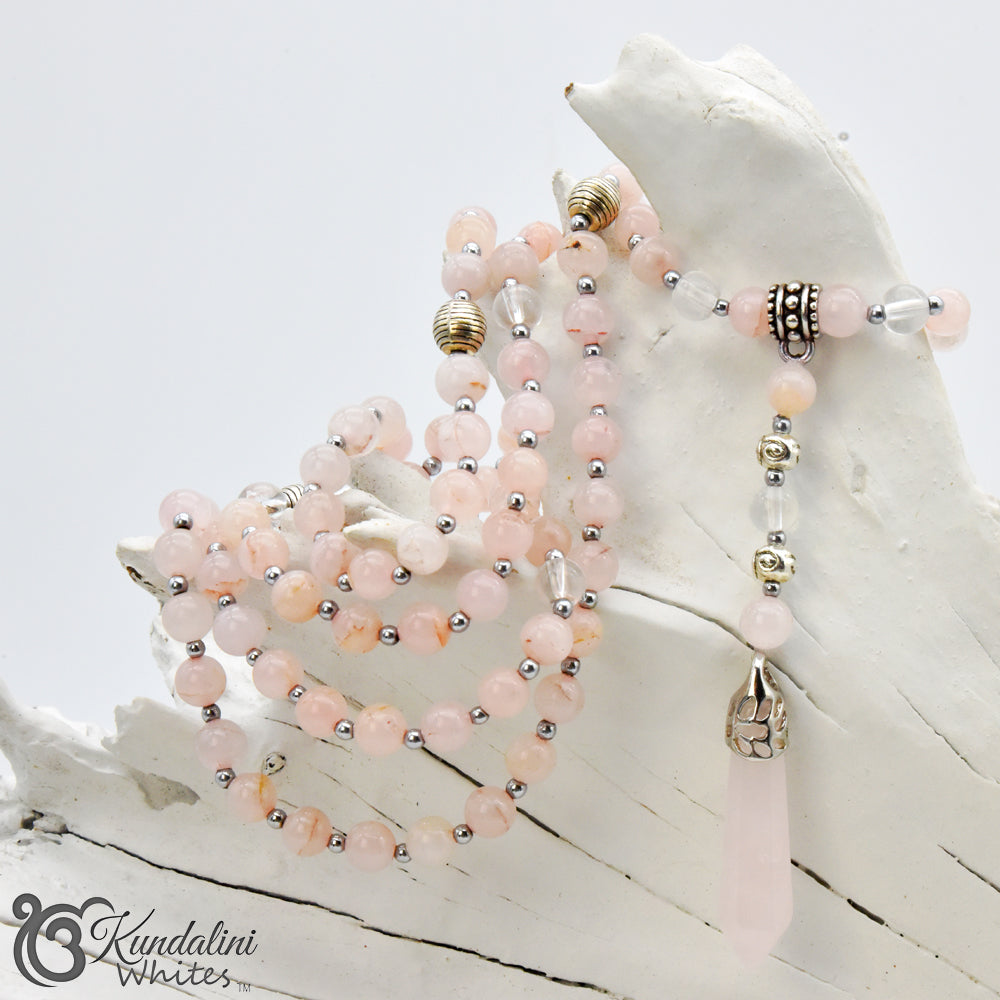 Mala necklace with pink and silver beads on a white surface, featuring the brand 'Kundalini'.