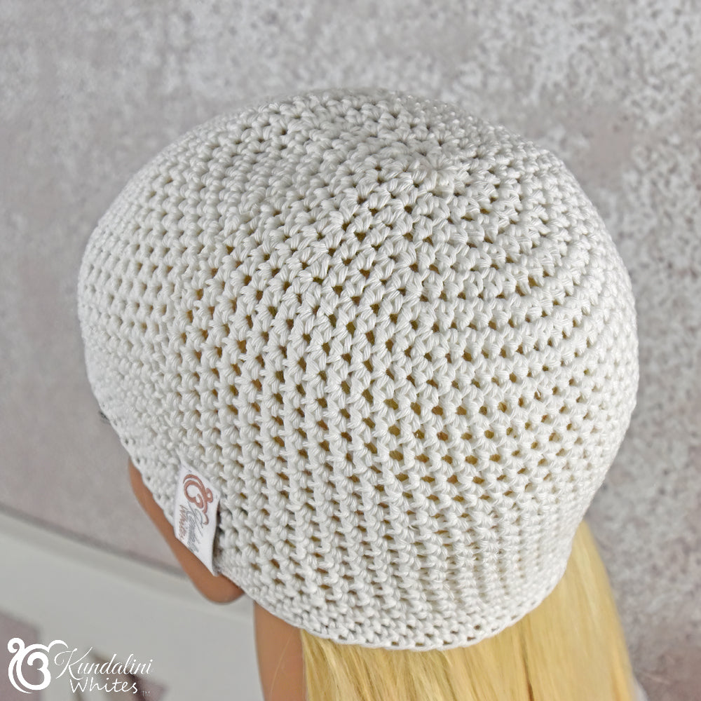 White crocheted beanie on a neutral background with 'Kundalini Whites' branding.