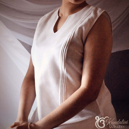 Person wearing a white sleeveless top with a blurred background