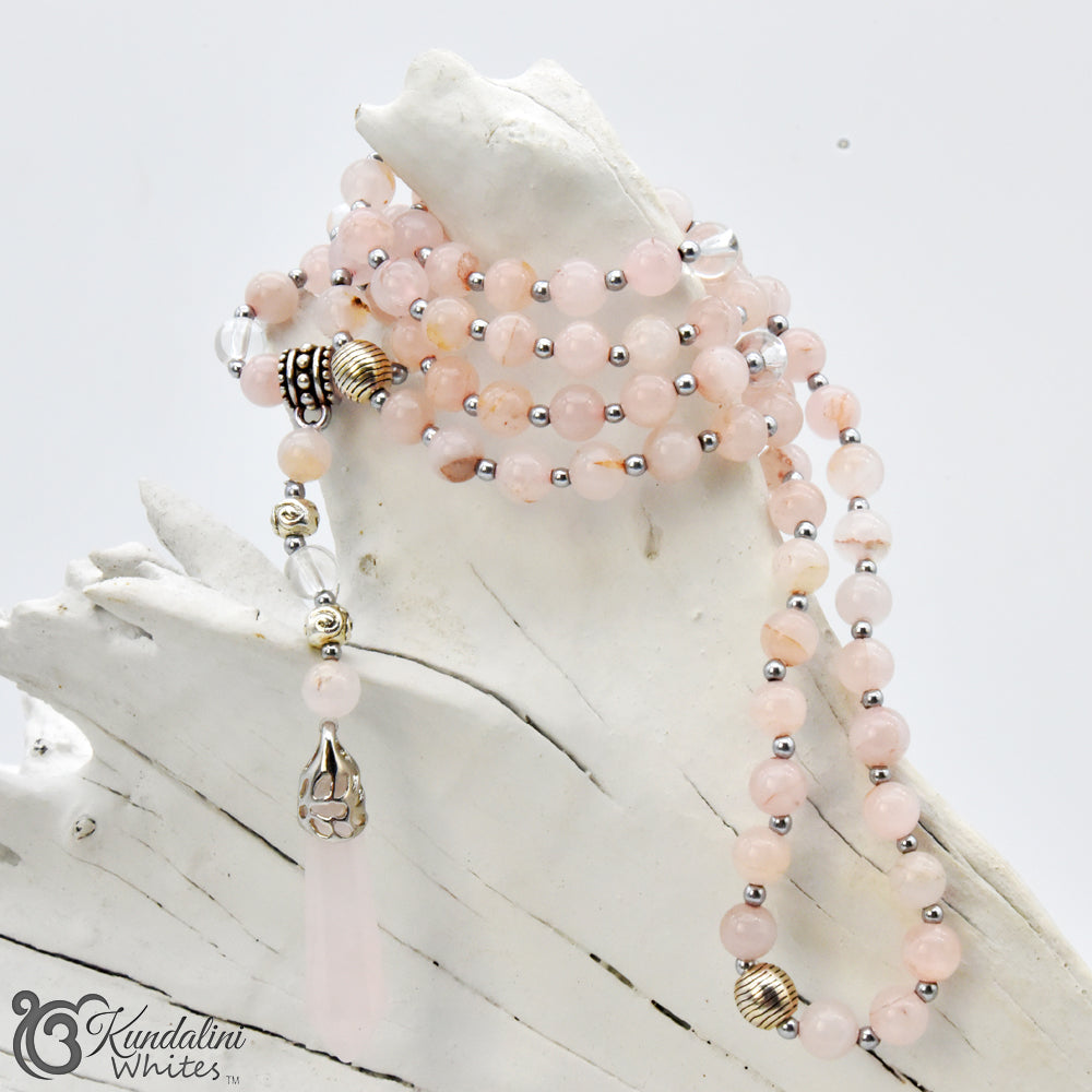 Mala necklace with pink and silver beads on a white shell