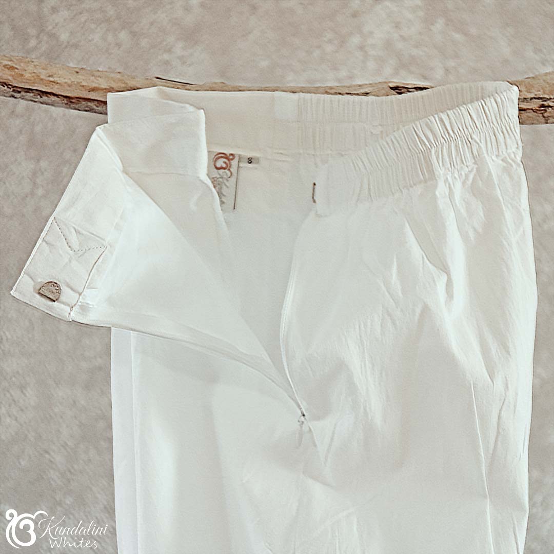 White pants hanging on a wooden rod against a beige wall.