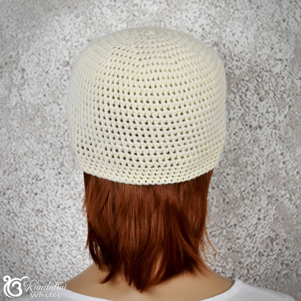 Person wearing an offwhite knitted beanie against a textured gray background