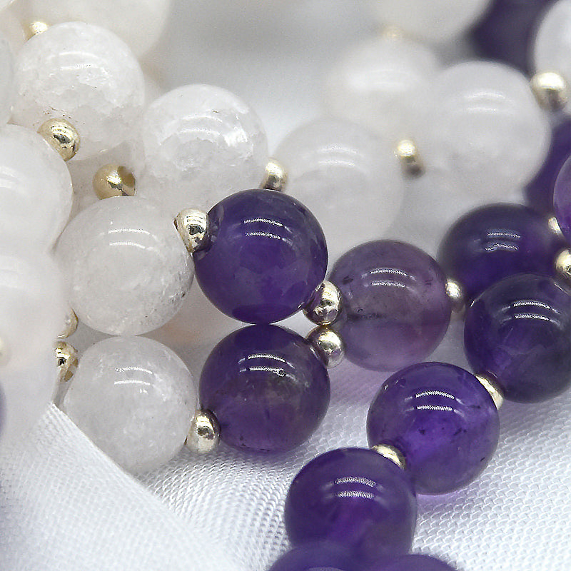 Close-up of a bracelet with white and purple beads on a white fabric background