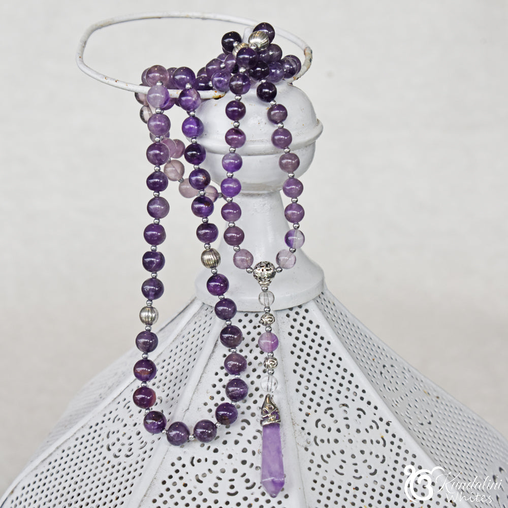 Purple beaded necklace with silver accents on a lantern against a white background