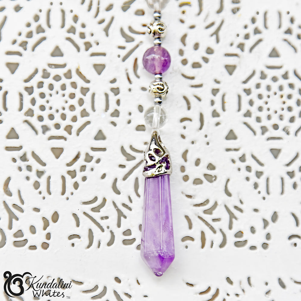 Purple crystal pendant necklace on a textured white background