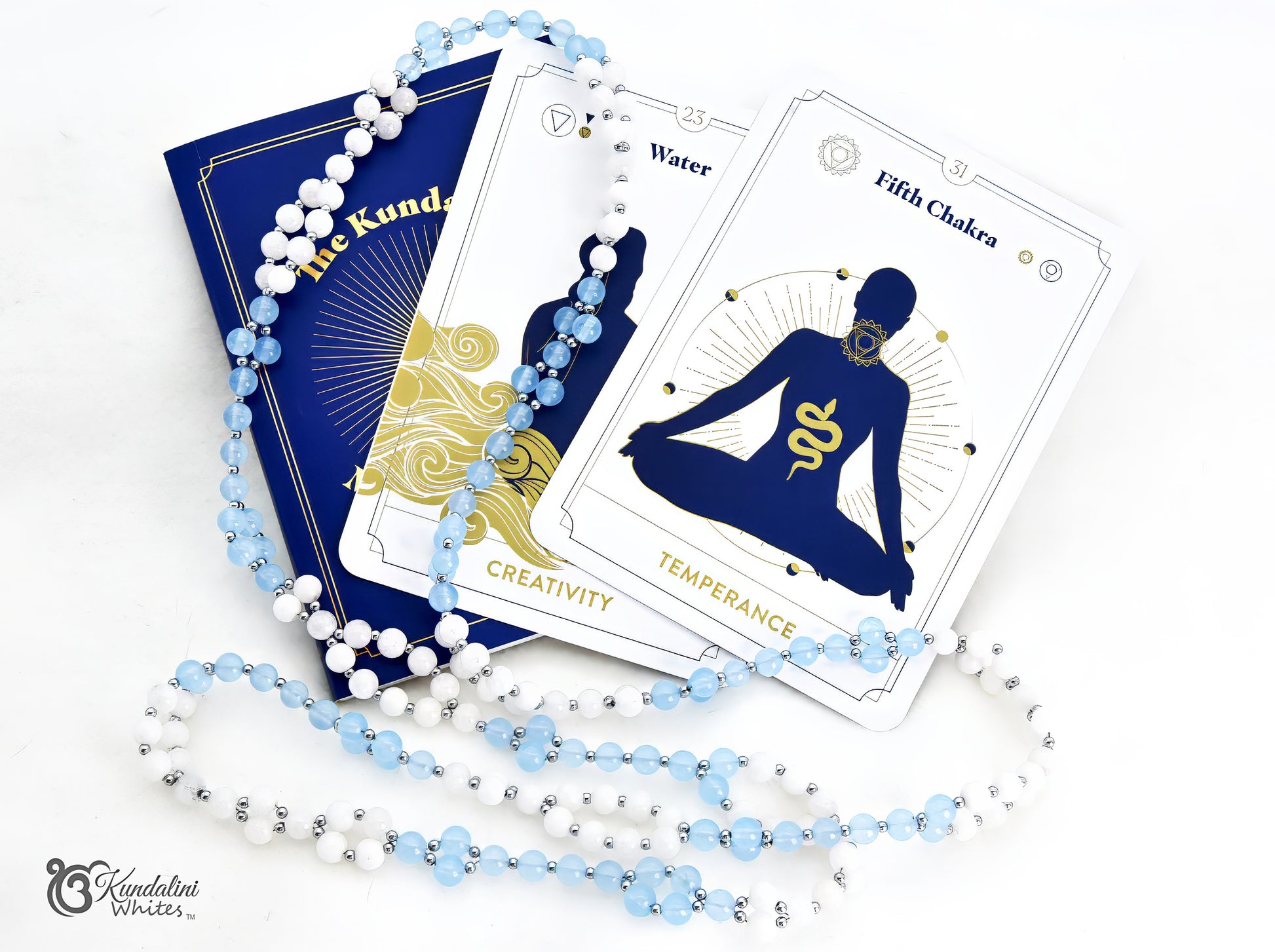 Two cards from The Kundalini Meditation Oracle Deck with an aquamarine and white agate Tantric Mala draped over them, photographed on a clean white background.