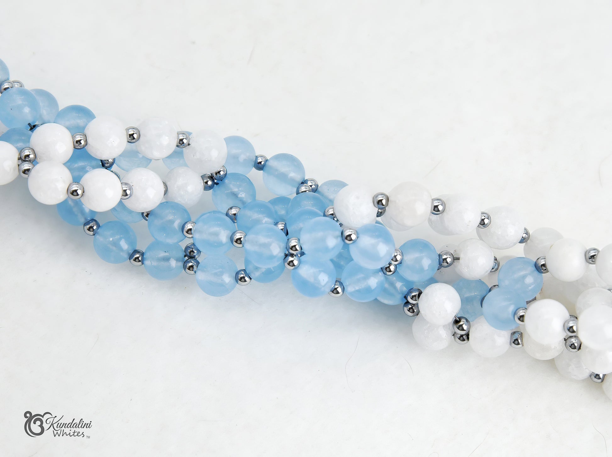 A close-up of an aquamarine and white agate Tantric Mala, arranged diagonally on a white background.