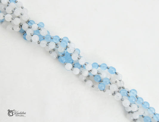 A close-up of an aquamarine and white jade Tantric Mala, arranged diagonally on a plain white background.