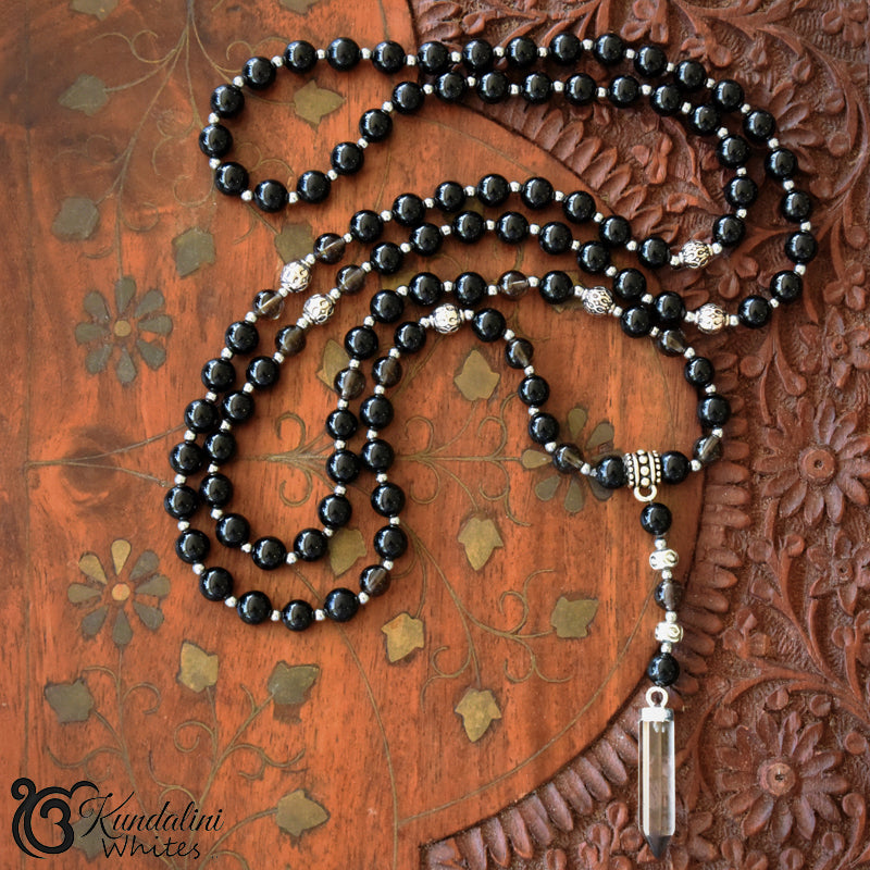 Black beaded Mala necklace with silver accents on a wooden surface