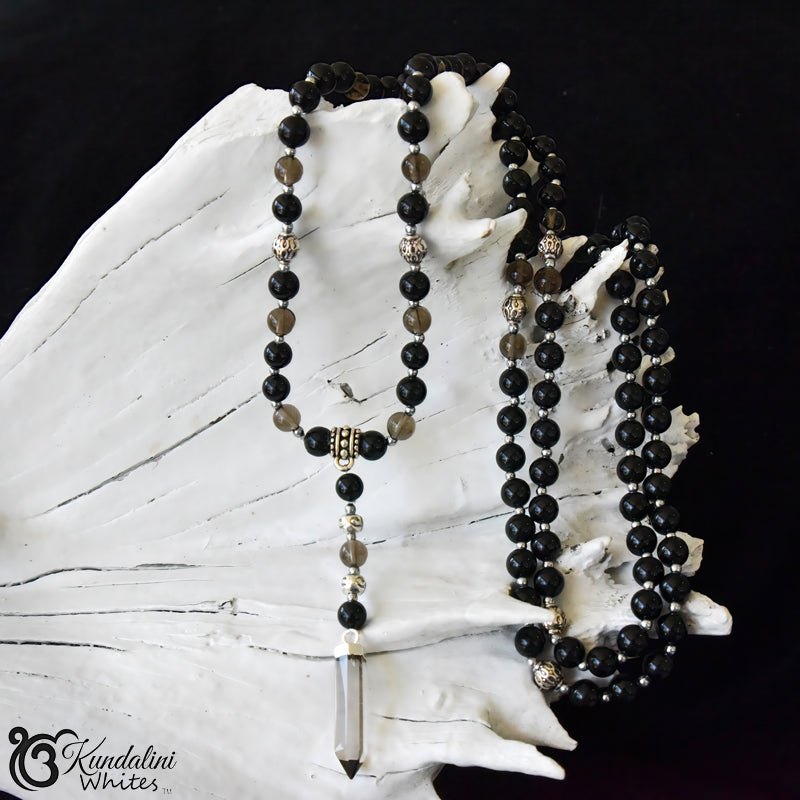 Black beaded necklace with a crystal pendant on a white shell against a black background